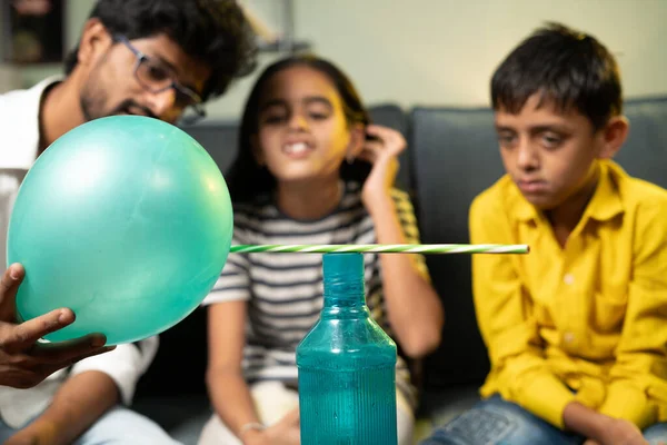 Kids at home in excited watching satic cling or static electric science experiment at home by showing pencil attracting to ballon - concept of childhood development and home learning and educatio — Stock Photo, Image