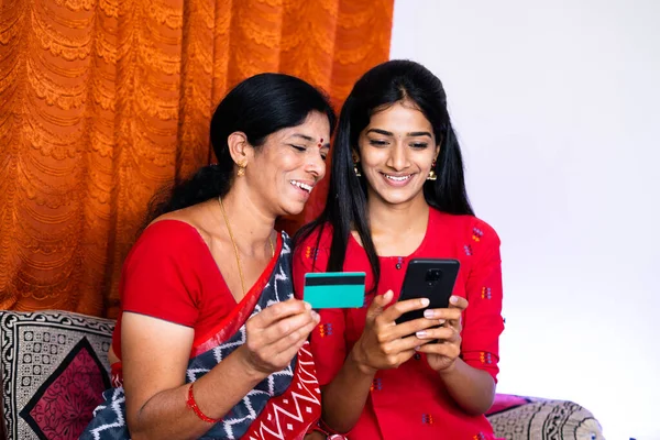 Індійська мати і дочка зайняті онлайн-платежем, використовуючи кредитну картку на мобільному телефоні вдома - концепція електронної комерції, банківської справи та фінансів. — стокове фото