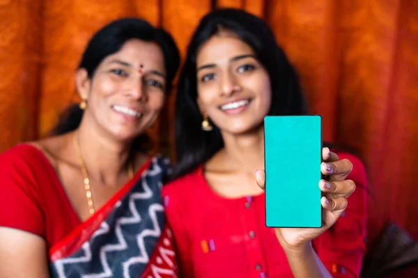 Індійська мати і дочка показують мобільний телефон з зеленим екраном, дивлячись на концепцію камери реклама, просування додатків і відносини. — стокове фото