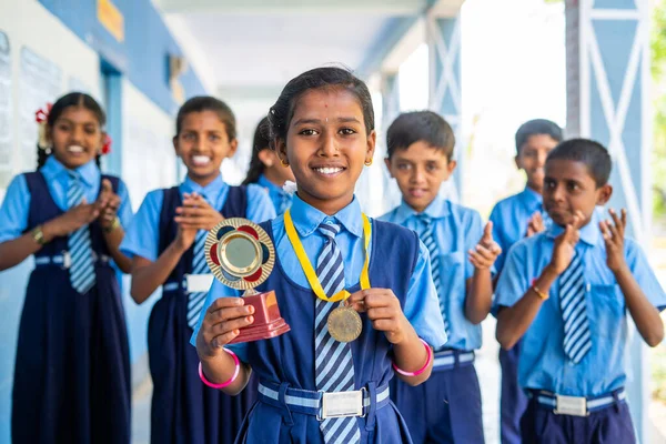 Περήφανο κορίτσι με τρόπαιο νικητή και μετάλλιο με χαρούμενους μαθητές να χειροκροτούν για την επιτυχία του παιδιού - πέπλο έμπνευσης, ενθάρρυνσης και νοημοσύνης — Φωτογραφία Αρχείου