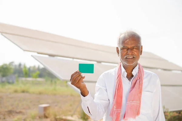 Köy çiftçisi, güneş panelleri önünde yeşil ekran boş kartını kameraya bakarak gösteriyor. Promosyon, reklam ve modern tarım kavramı.. — Stok fotoğraf