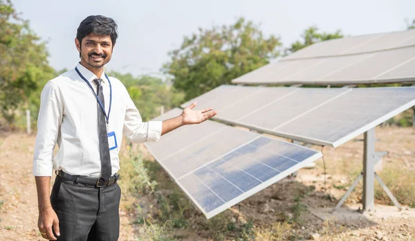Tarım arazisindeki güneş enerjisi panellerini gösteren mutlu gülümseyen mühendis - yenilenebilir enerji, sürdürülebilir yaşam tarzı ve yatırım ve bankacılık için destek kavramı — Stok fotoğraf