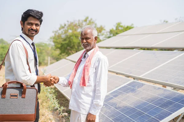 Çiftçiye odaklan Köy çiftçisi bankeri güneş paneli önünde el sıkışarak selamlıyor - destek ya da yardım kavramı, iletişim ve sürdürülebilir yaşam tarzı — Stok fotoğraf