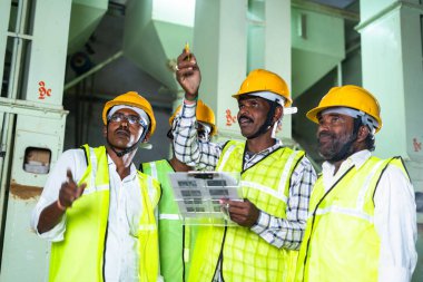 Endüstriyel işçiler fabrikada çalışan makineleri tartışıyorlar - iletişim, liderlik ve takım çalışması kavramı.