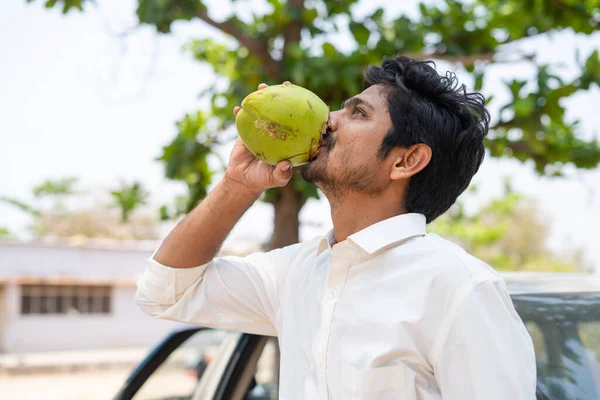 Jeune homme assoiffé buvant de l'eau de coco fraîche en été - concpet de rafraîchissement, de canicule et de détente — Photo