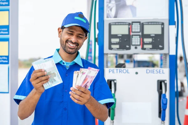 Asistente de gasolinera sonriente contando dinero en la gasolinera - concepto de beneficio empresarial, ganancias, salario y finanzas —  Fotos de Stock