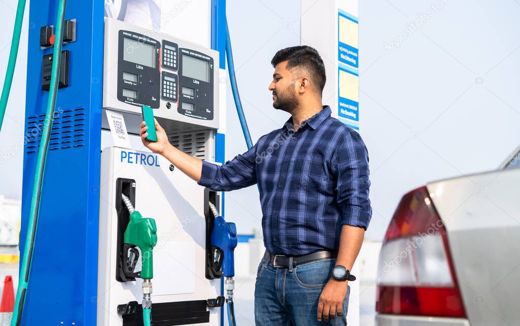 customer paying at pertrol bump by scanning QR code using mobile phone after refuling car - concept of digital contact less payment, wireless transaction and petroleum service