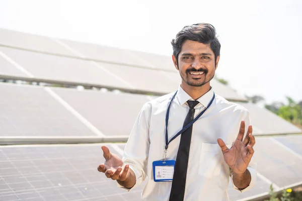 Profesyonel mühendis kameraya bakarak tarım arazisindeki güneş paneli kurulumunu açıklıyor. Yenilenebilir enerji, çevre dostu ve teknolojinin birleşimi. — Stok fotoğraf
