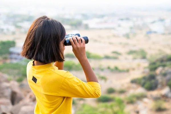 Niña viendo destinos lejanos usando binocular en la cima de la colina durante el campamento de verano - concepto de exploración, expedición y vacaciones. — Foto de Stock