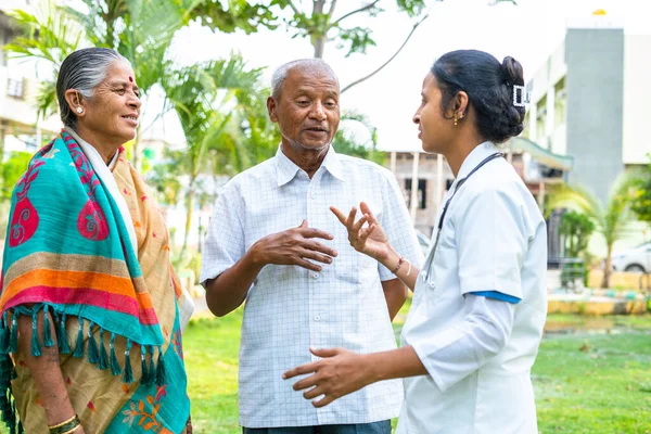Senior old couple busy discussing with nurse at park outside the hospital - concpet of healthcare, consultation and assistance. — Stock Photo, Image