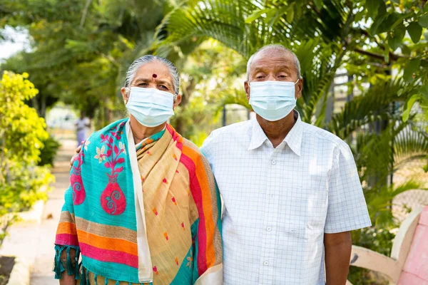 Parkta sabah yürüyüşü sırasında tıbbi maskeli yaşlı çiftler - covid-19 Coronavirus koruması, sağlık ve güvenlik kavramı. — Stok fotoğraf