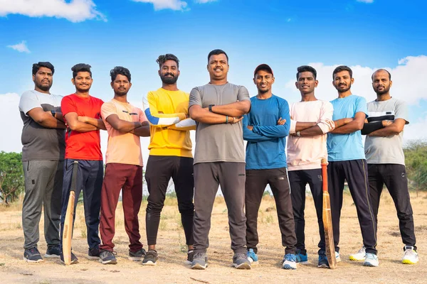 Fullshot, group of Confident cricket players standing with arms crossed by looking camera at playground - concept of teamwork, sportsmanship and champions. — стоковое фото