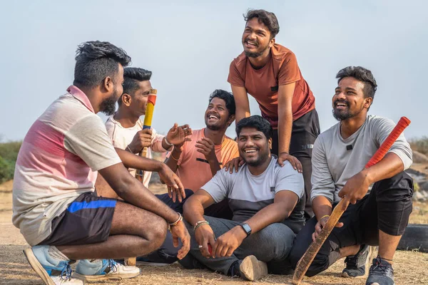 Игроки в крикет разговаривают друг с другом после занятий спортом, сидя на детской площадке - концепция дружбы, перерыва и общения — стоковое фото
