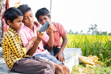 Hint köyü gençleri cep telefonuyla bilgisayar oyunu oynuyor. Paddy Field yakınlarında. Teknoloji, birliktelik ve gelişme kavramı.