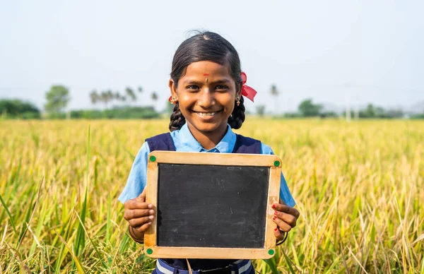 Ευτυχισμένο χαμογελαστό παιδί σχολείο κρατώντας άδειο πίνακα πλάκα κοντά στον τομέα paddy - έννοια της εκπαίδευσης, της μάθησης και της χειραφέτησης της παιδικής ηλικίας — Φωτογραφία Αρχείου
