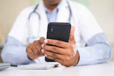 Doktorun hastanedeyken cep telefonu kullandığı yakın çekim - sanal doktor konsepti, ara verme ve sağlık hizmeti.
