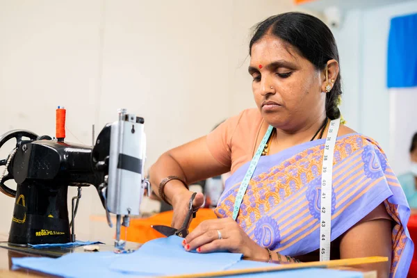 Donna indiana a indumenti impegnati a lavorare tagliando i vestiti vicino alla segatrice concetto di responsabilizzazione, competenza e piccola impresa — Foto Stock