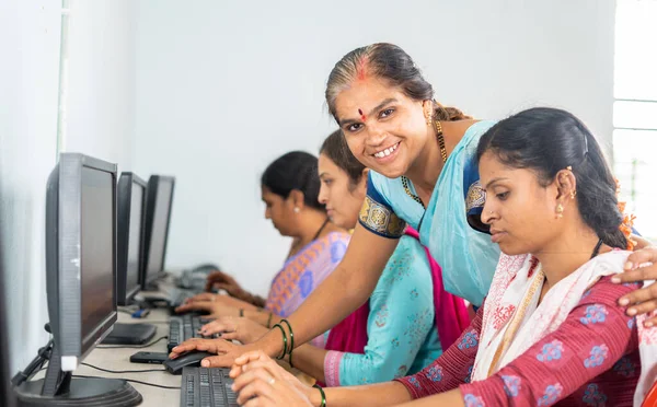 마을 여성들에게 컴퓨터 수업을 가르치면서 미소짓는 교사들 이 카메라를 보고 있는 모습 - 자원 봉사, 자기 고용 훈련 및 권한 부여 프로그램의 개념 - — 스톡 사진