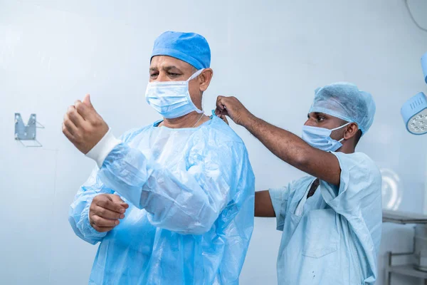 Медсестра, яка допомагає хірургу носити в операційному театрі для хірургії концепція професійної професії, досвіду та допоміжного персоналу . — стокове фото