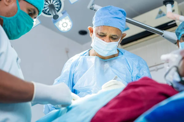 Cirujano concentrado ocupado realizando cirugía al paciente enfermo en el quirófano - concepto de experiencia, especialista y tratamiento profesional —  Fotos de Stock