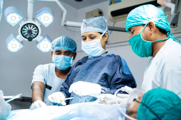 Woman surgeon with supporting practitioners busy doing surgery at operating room - concept of teamwork, healthcare treatment and woman empowerment. — 스톡 사진