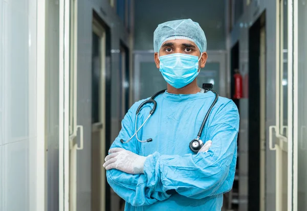 Cirujano de pie con brazos cruzados con estetoscopio de sujeción mirando a la cámara en el pasillo del hospital - concepto de confianza, atención médica y ocupación profesional —  Fotos de Stock