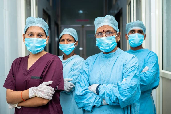 Група хірургів і практиків впевнені, що стоять зі зброєю, що перетинається, дивлячись камеру в лікарняному коридорі концепція охорони здоров'я та медичної служби — стокове фото