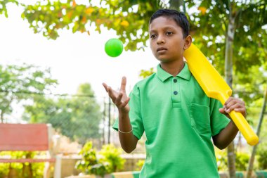 Kriket sopalı ve toplu ciddi bir çocuk, kendine güvenen, ciddi oyun konsepti ve hafta sonu tatil aktiviteleri için bekliyor.