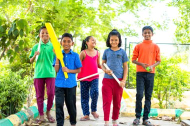 Kriket topu, sopa ve kütüklü bir grup çocuk bahçede kriket oynamaya geliyor. Genç şampiyonlar, çocukluk ve mutluluk kavramı..