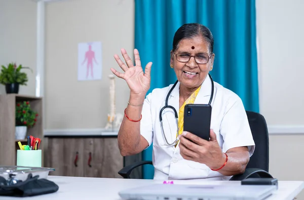 Medico senior in videochiamata con paziente sul cellulare in ospedale - concetto di consultazione virtuale, assistenza sanitaria e comunicazione — Foto Stock