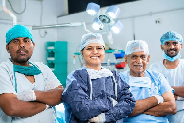 Група усміхнених успішних хірургів, що стоять впевнено, дивлячись на камеру в операційному театрі - концерт фахівців охорони здоров'я, досвід та кар'єра . — стокове фото