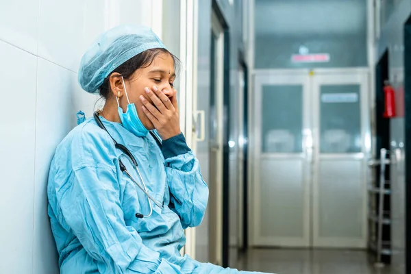 Bostezo cirujano sentado en el pasillo del hospital después de la cirugía cerca del quirófano - concepto de agotamiento, exceso de trabajo y aburrimiento —  Fotos de Stock