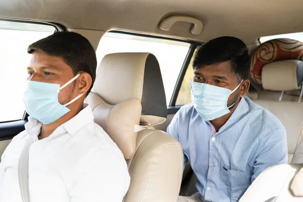 Passanger with Taxi driver talking about destination while both in mask due coronavirus pandemic - concept of traveling with covid safely precautions, back to business and pollution — стоковое фото