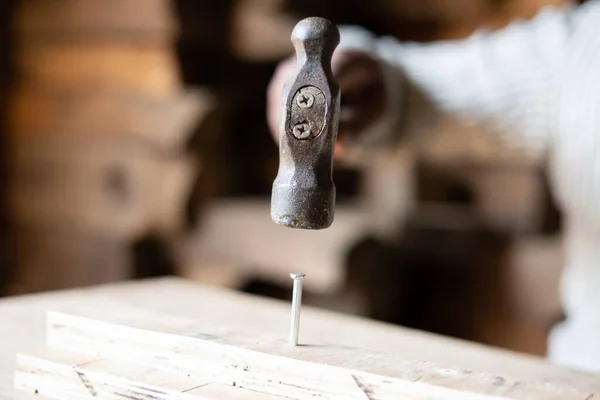 Primo piano colpo di mani di falegname colpire chiodo al legno con martello in negozio - concetto di officina, falegname e artigiano — Foto Stock
