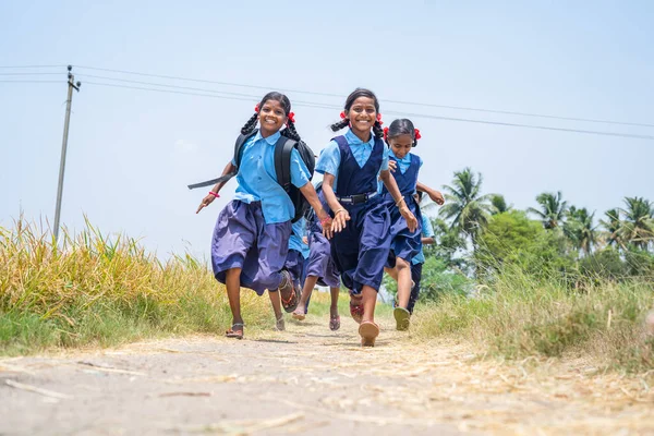 Ομάδα των κοριτσιών σχολείο τρέχει στο σπίτι σε αγώνα μετά το σχολείο κοντά σε αγρόκτημα γης στο χωριό - έννοια του ενθουσιασμένοι, χαρούμενα και ενεργητικός — Φωτογραφία Αρχείου