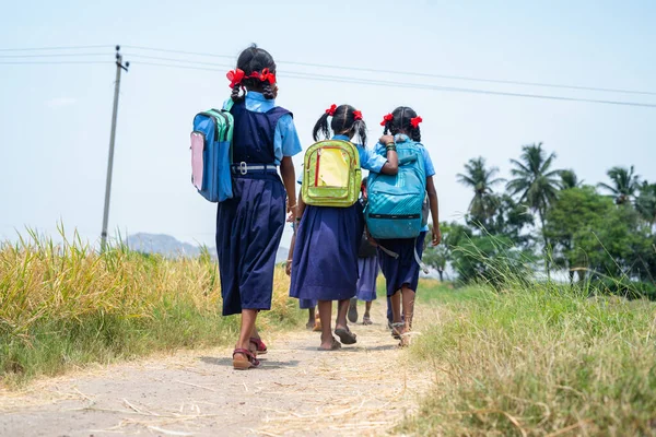 Back view shot of village kids in uniform going home from school after class - έννοια της εκπαίδευσης, παιδική ηλικία και φιλία — Φωτογραφία Αρχείου