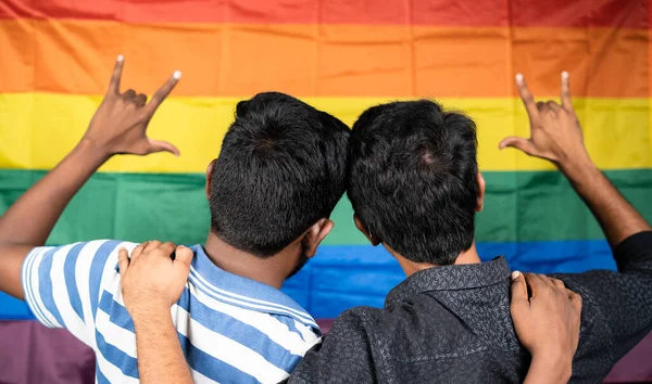 Widok z tyłu młody mężczyzna para pokazując znak miłości przed dumy lub tęczy flagi, koncepcja lgbtq — Zdjęcie stockowe