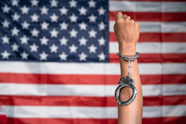 Close up shot of hanads rising with released cuffs against us or american flag as background - concept of juneteenth, freedom and justice. — Fotografia de Stock
