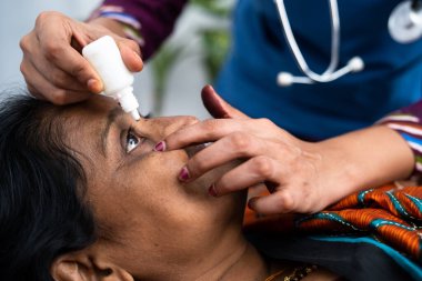 Yatakta yatan hasta orta yaşlı kadına göz damlası damlatan hemşire ya da doktor - terapi, tedavi ve sağlık desteği kavramı.
