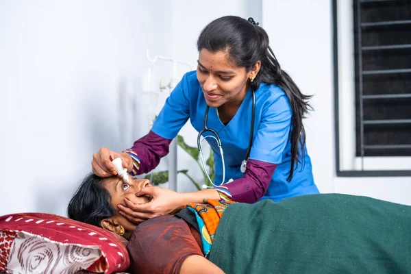 Yatakta yatan hasta orta yaşlı kadına göz damlası damlatan hemşire ya da doktor - terapi, tedavi ve sağlık desteği kavramı.