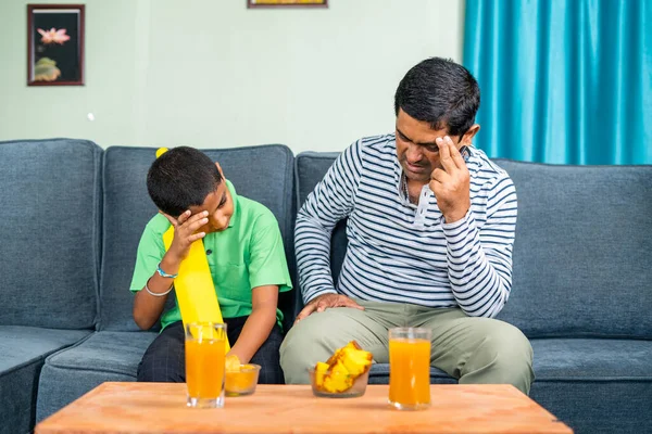Father and son got upset while watching live cricket game at home due to loss of match or wicket - concept of entertainment, sports fans and unhappy.