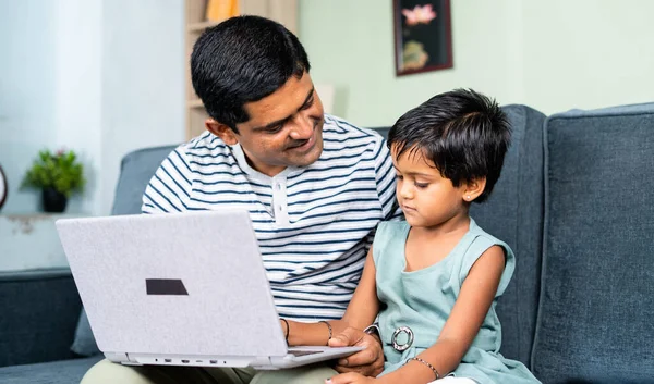 happy Father helping or teaching the daughter to use laptop at home - concept of home schooling, parental teaching and development.