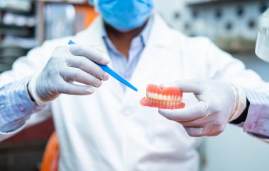 Diş hekimlerinin klinikteki yakın çekimleri kameraya bakarken takma diş takmak suretiyle diş çürükleri hakkında tavsiyelerde bulunmaları veya bilgi vermeleri - profesyonel meslek mesleği ve diş bakımı tavsiyeleri kavramı