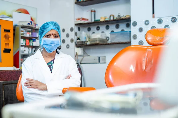 Woman dental doctor with crossed arms at hospital by looking at camera while sitting on chair - concept profesional occupation, hygienist and oral care