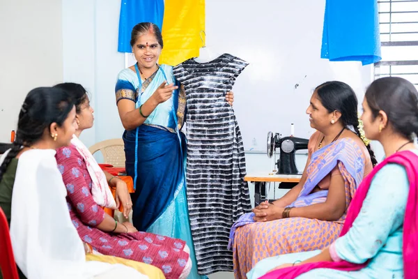 Woman teaching cloth design to students at tailoring training centre - concept of learning, employment and workshop