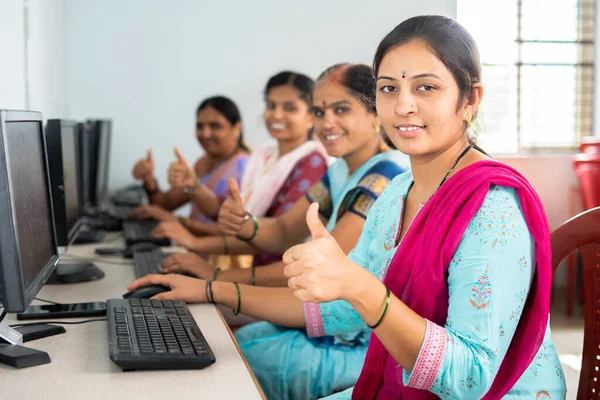 group of smiling women showing thumbs up by looking camera during computer training class - concept of women employment, learning and education.