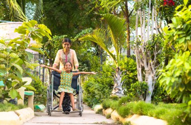 Anne engelli çocuğu parkta tekerlekli sandalyeyle yürürken alıyor. Annelik, şefkat ve rahatlama kavramı.