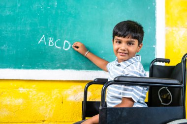Young teenger school kid with disability on wheel chair writing on board while looking at camera - concept of education, growth and development.