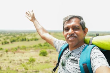 Yaş sınırı geçmiş seyahat vlogcusunu sırt çantasıyla kamerayla tepenin üstünde tutarak konuşmak - içerik yaratıcısı, yürüyüş ve özgürlük kavramı.