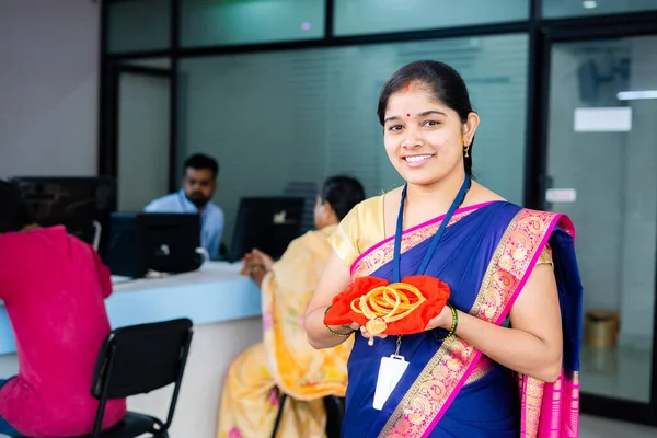 happy smiling woman at bank with gold jewelry in hand looking camera at bank - concept of gold loan, financial or banking service and investment plans